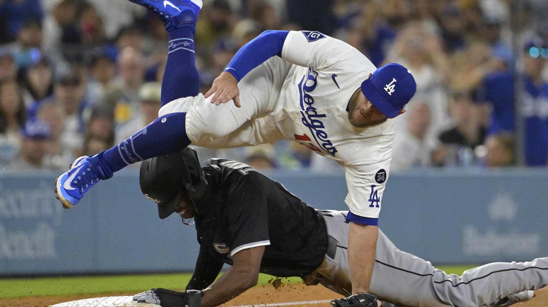 Los Angeles Dodgers third baseman Max Muncy (13) is injured as he flips over Chicago White Sox right fielder Michael A. Taylor (21) after tagging him out in the sixth inning at Dodger Stadium.
