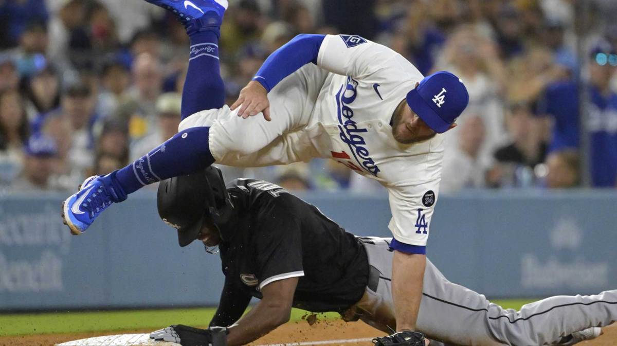 Los Angeles Dodgers third baseman Max Muncy (13) is injured as he flips over Chicago White Sox right fielder Michael A. Taylor (21) after tagging him out in the sixth inning at Dodger Stadium.