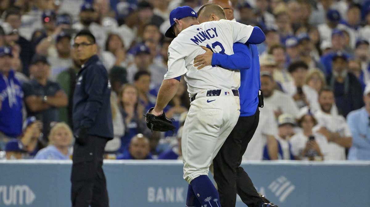 Los Angeles Dodgers third baseman Max Muncy (13) is helped off the field after he was injured on a play during the fifth inning against the Chicago White Sox at Dodger Stadium.