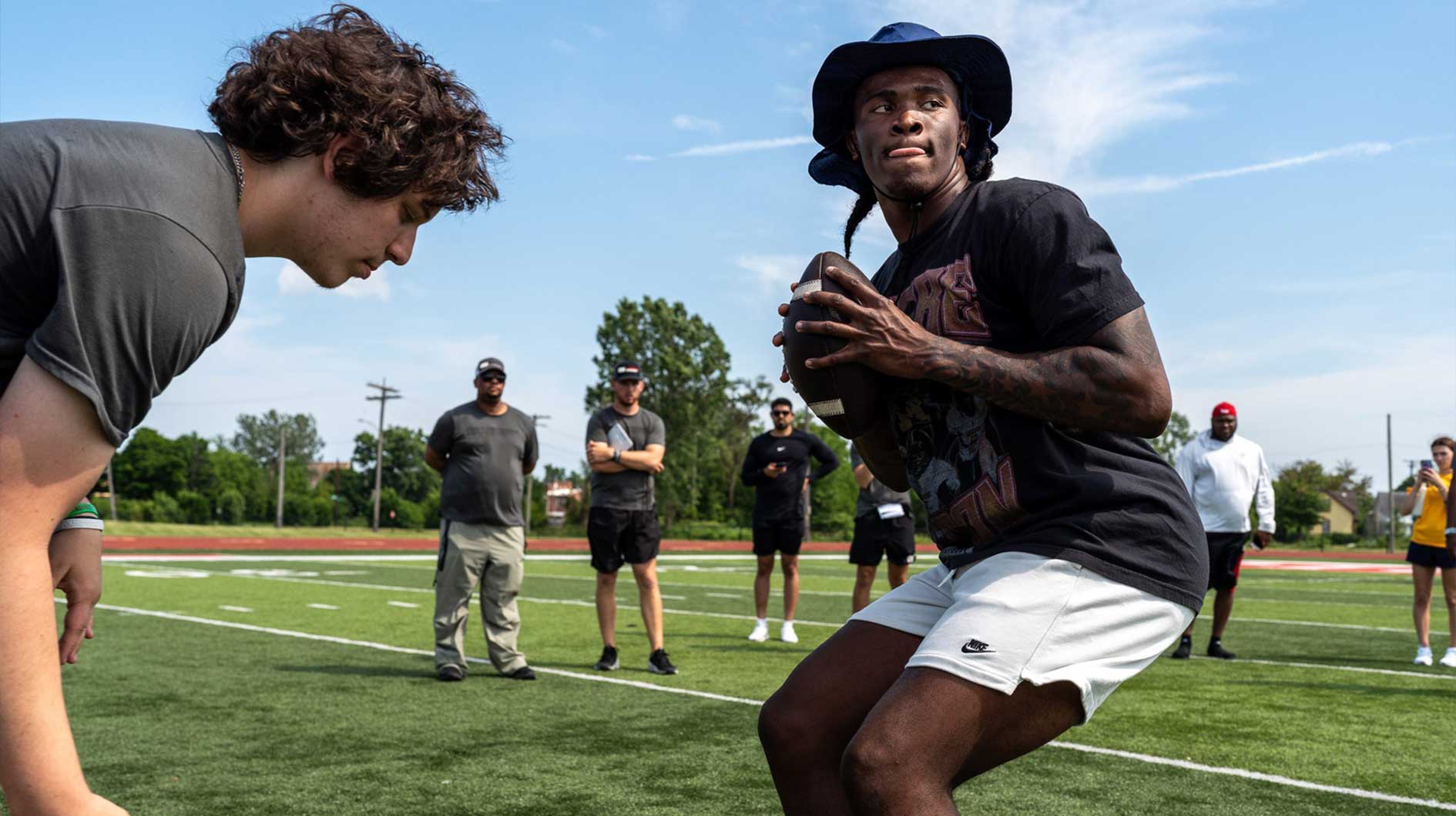 Josh Putman, 19, a member of Quarterback University, snaps the ball to Bryce Underwood, 17, a freshman quarterback at Michigan, during a private workout in Detroit on Saturday, June 21, 2025.
