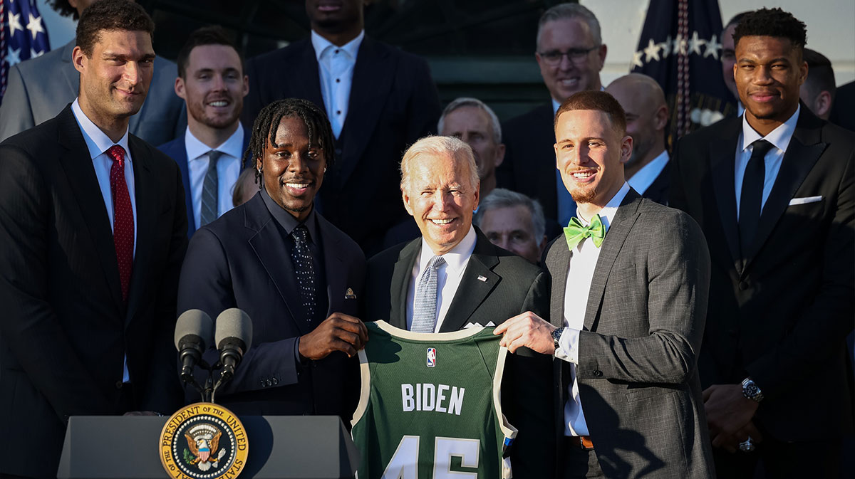 US President Joe Biden (Center) is held with Milwaukee Bucks Jrue Holiday players (left) and Donte Divincenzo (right) during a ceremony to honor the team of his NBA championship on the southern lawn of the White House.