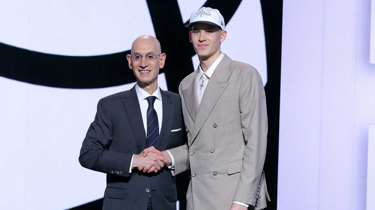 Nets' Egor Demin stands with NBA commissioner Adam Silver after being selected as the eighth pick by the Brooklyn Nets in the first round of the 2025 NBA Draft at Barclays Center with Blazers' Yang Hansen in the background