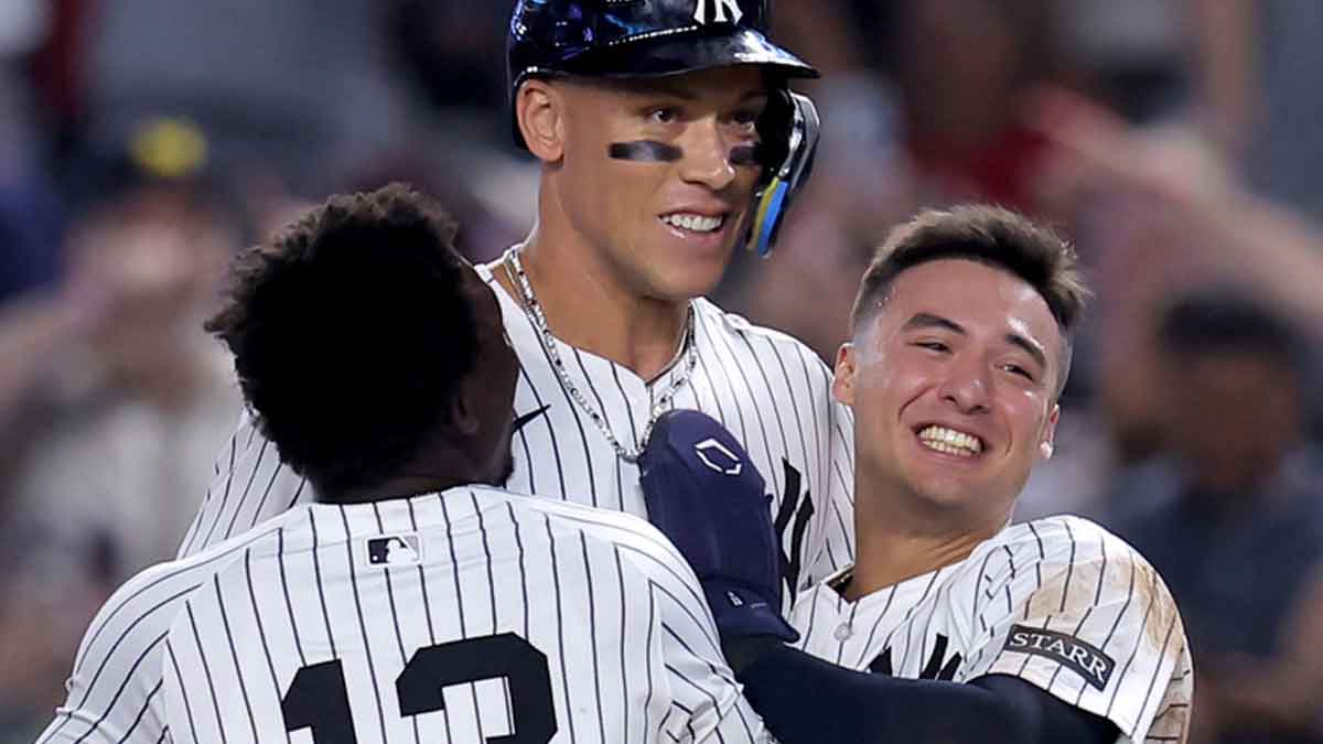 New York Yankees designated hitter Aaron Judge (99) celebrates with shortstop Anthony Volpe (11) and second baseman Jazz Chisholm Jr. (13) after his tenth inning walkoff sacrifice fly against the Seattle Mariners at Yankee Stadium.
