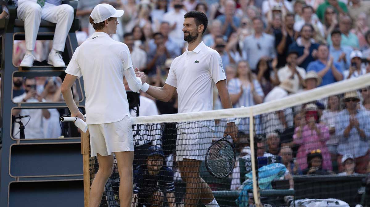 Jannik Sinner of Italy at the net with Novak Djokovic of Serbia after their match on day 12 at All England Lawn Tennis and Croquet Club.