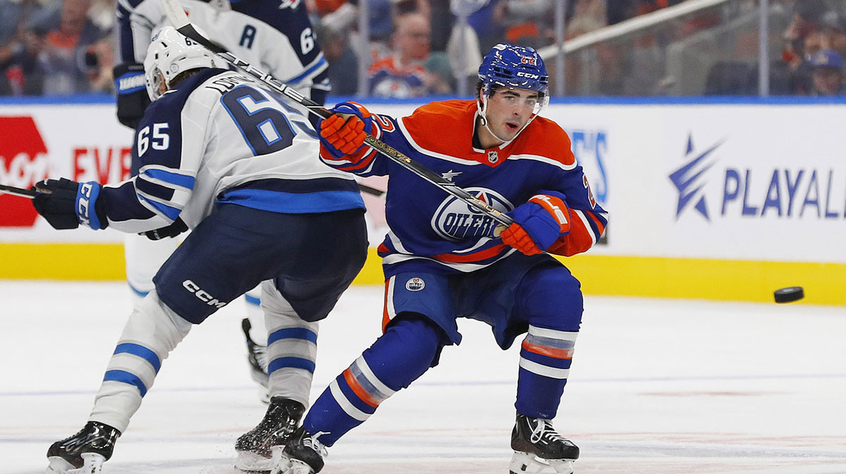 Edmonton Oilers Forward Matt Savoie (22) battles with Winnipeg Jets forward Markus Loponen (65) while keeping an eye on a loose puck at Rogers Place.