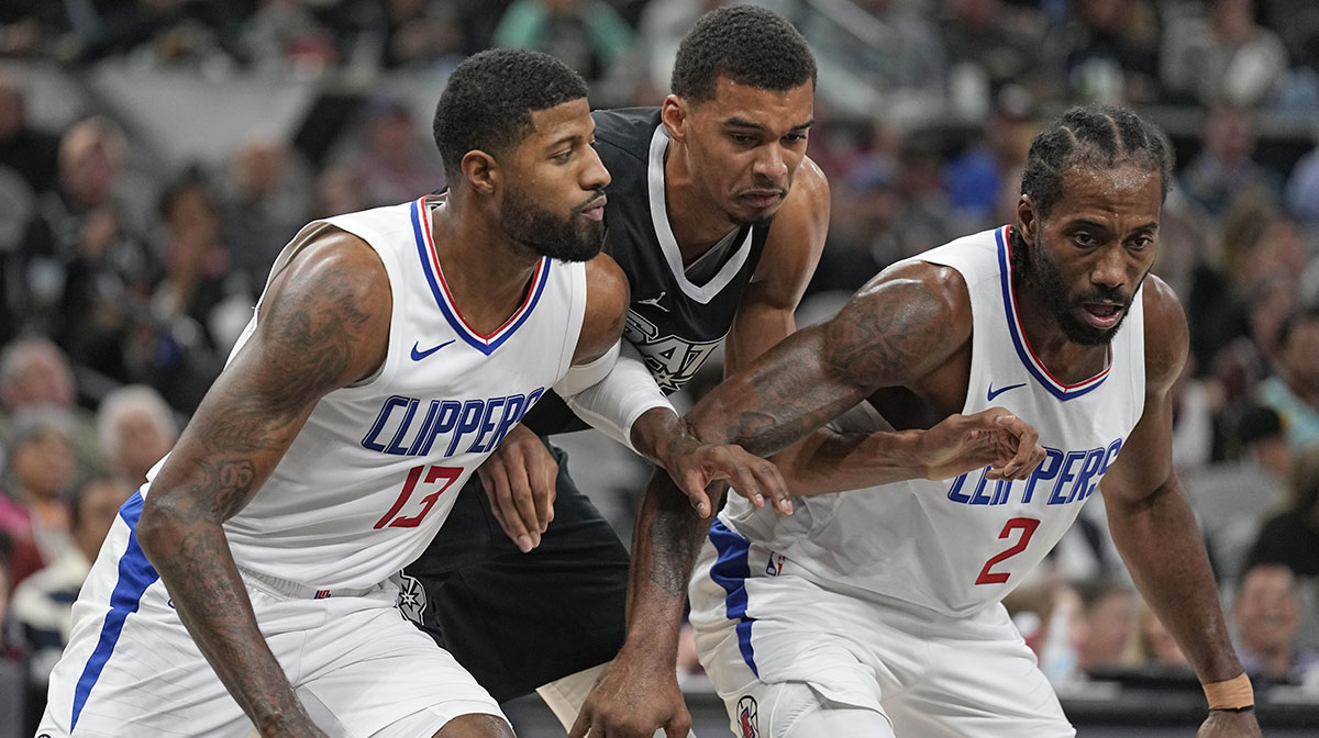 Los Angeles Clippers forwards Paul George (13) and Kawhi Leonard (2) box out San Antonio Spurs forward Victor Wembanyama (1) during the second half at Frost Bank Center.