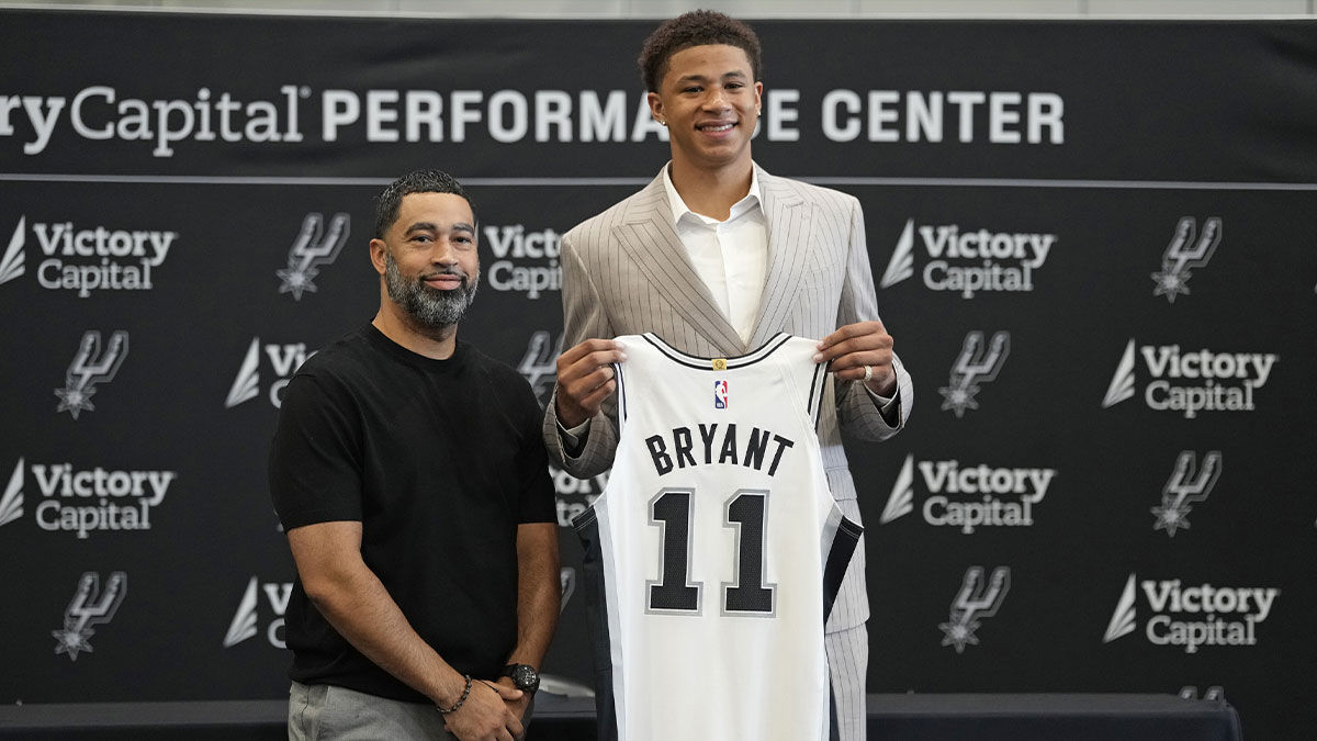 San Antonio first round draft pick Carter Bryant (11) holds up his jersey along with general manager Brian Wright at Victory Capital Performance Center.