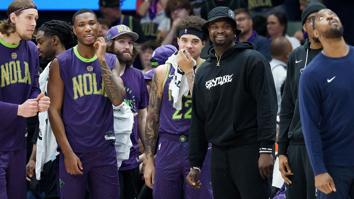 New Orleans Pelicans forward Zion Williamson, wearing street clothes and hat, smiles as his team gains a lead late during the fourth quarter against the Charlotte Hornets at Smoothie King Center.