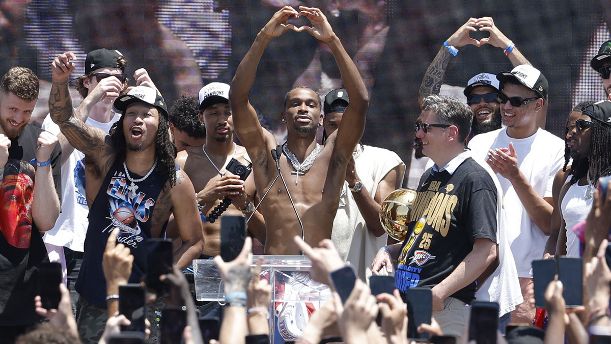 Thunder guard Shai Gilgeous-Alexander, center, holds up a heart shape with his hands for fans during the Oklahoma City Thunder Champions parade with Oklahoma City Mayor David Holt