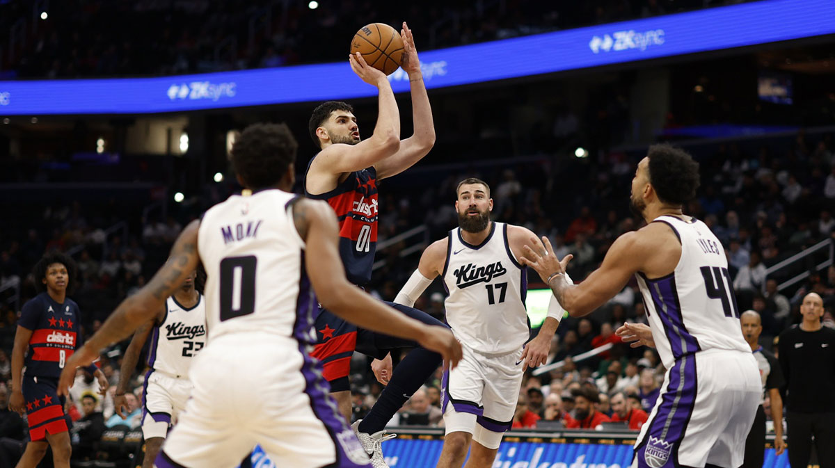 Washington Wizards forward Tristan Vukcevic (00) shoots the ball as Sacramento Kings center Jonas Valanciunas (17) and Kings forward Trey Lyles (41) defend in the second half at Capital One Arena.