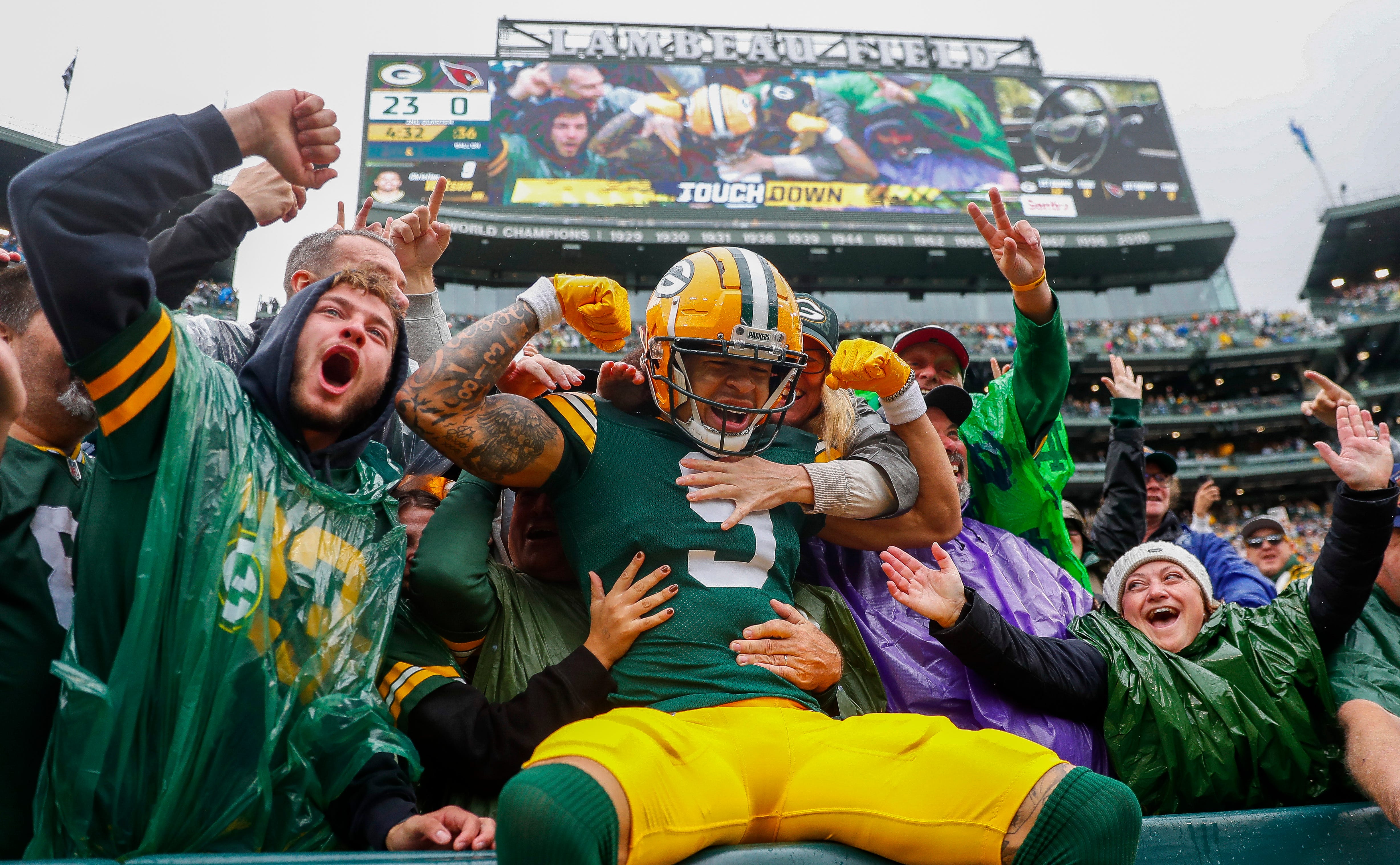 Green Bay Packers wide receiver Christian Watson (9) flexes as he does a “Lambeau Leap” with Packers fans after scoring a touchdown against the Arizona Cardinals on Sunday, October 13, 2024, at Lambeau Field in Green Bay, Wis. The Packers won the game, 34-13.