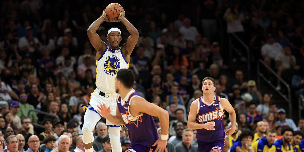 Warriors forward Jimmy Butler III (10) makes a pass in front of Phoenix Suns guard Devin Booker (1) during the first half at Footprint Center