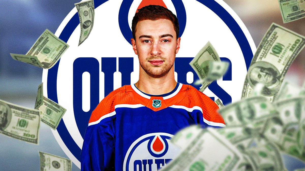 Andrew Mangiapane in an Oilers jersey, oilers logo in the background money around him.