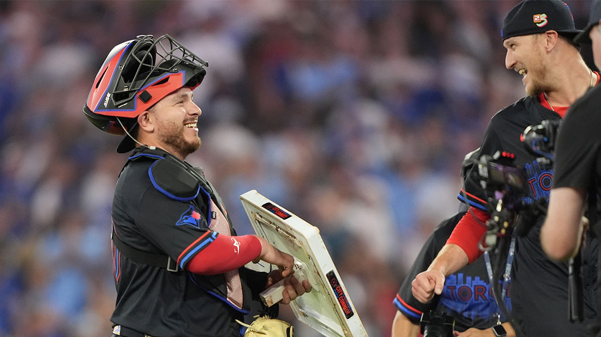 Toronto Blue Jays pitcher Jeff Hoffman (23) laughs with catcher Alejandro Kirk (30) as he holds onto his first stolen MLB base after a win over the Texas Rangers at Rogers Centre.