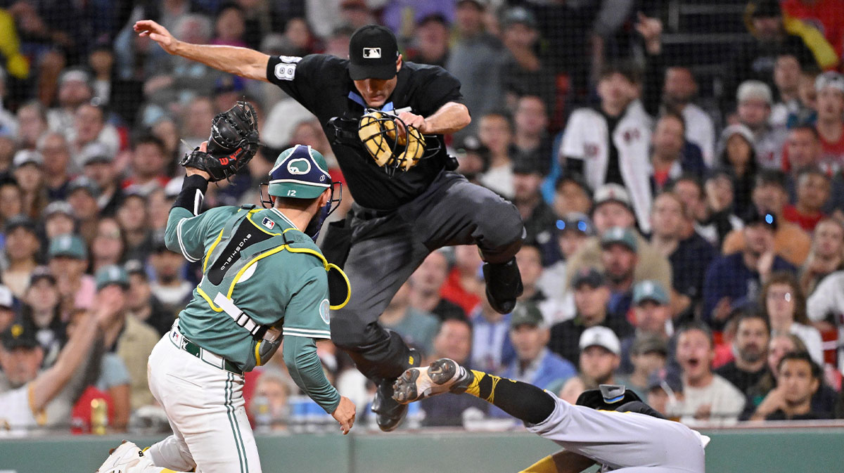 MLB umpire Dan Iassogna (58) jumps out of the way as Pittsburgh Pirates second baseman Ronny Simon (63) slides across home plate against Boston Red Sox catcher Connor Wong (12) during the eighth inning at Fenway Park.