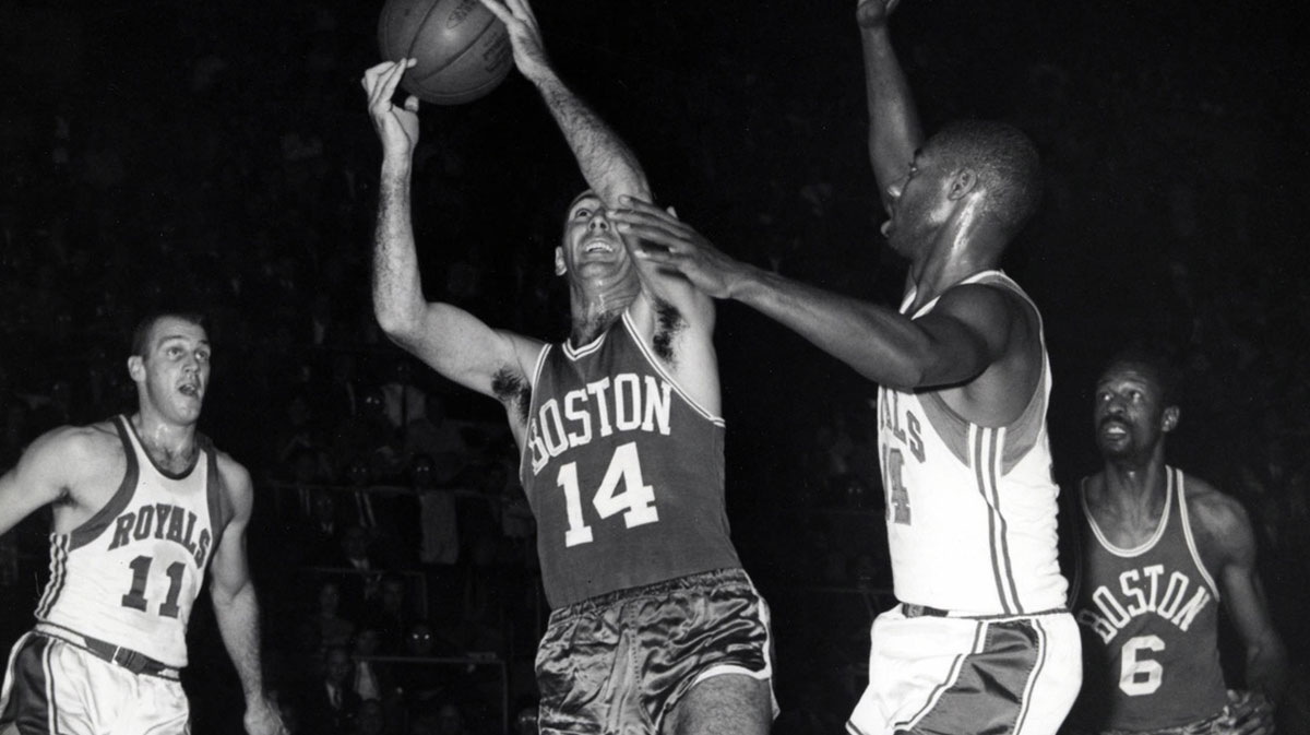 Boston Celtics guard Bob Cousy (14) drives to the basket against Cincinnati Royals guard Oscar Robertson (14) and Arlen Brockhorn (11) as Bill Russell (6) looks on at Cincinnati Gardens.