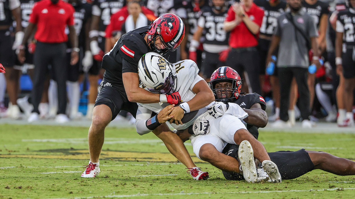 UCF Knights quarterback Cam Fancher (14) is sacked by Jacksonville State Gamecocks defensive end Emmanuel Oyebadejo (99) during the first quarter at Acrisure Bounce House.