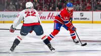 Montreal Canadiens center Nick Suzuki (14) plays the puck against Washington Capitals right wing Brandon Duhaime (22) during the third period in game four of the first round of the 2025 Stanley Cup Playoffs at Bell Centre.