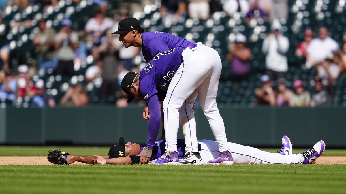 Colorado Rockies relief pitcher Juan Mejia (47) lays on the ground after securing the final out as first baseman Warming Bernabel (25) and second baseman Ryan Ritter (8) react in the ninth inning against the Arizona Diamondbacks at Coors Field.