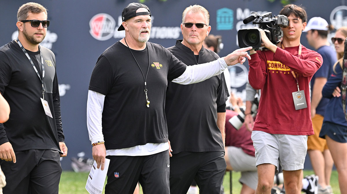 Washington Commanders head coach Dan Quinn (pointing) walks to the podium for a press conference before training camp at Gillette Stadium.