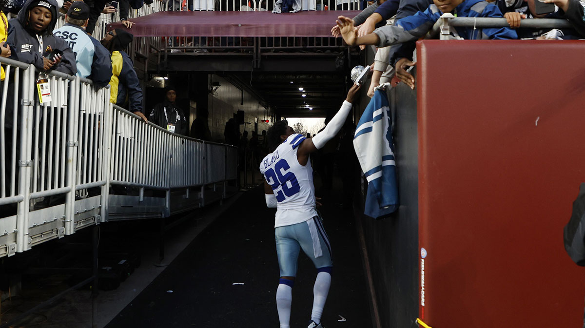 Dallas Cowboys cornerback DaRon Bland (26) hands a piece of his equipment to a fan while leaving the field after the Cowboys' game against the Washington Commanders at Northwest Stadium.