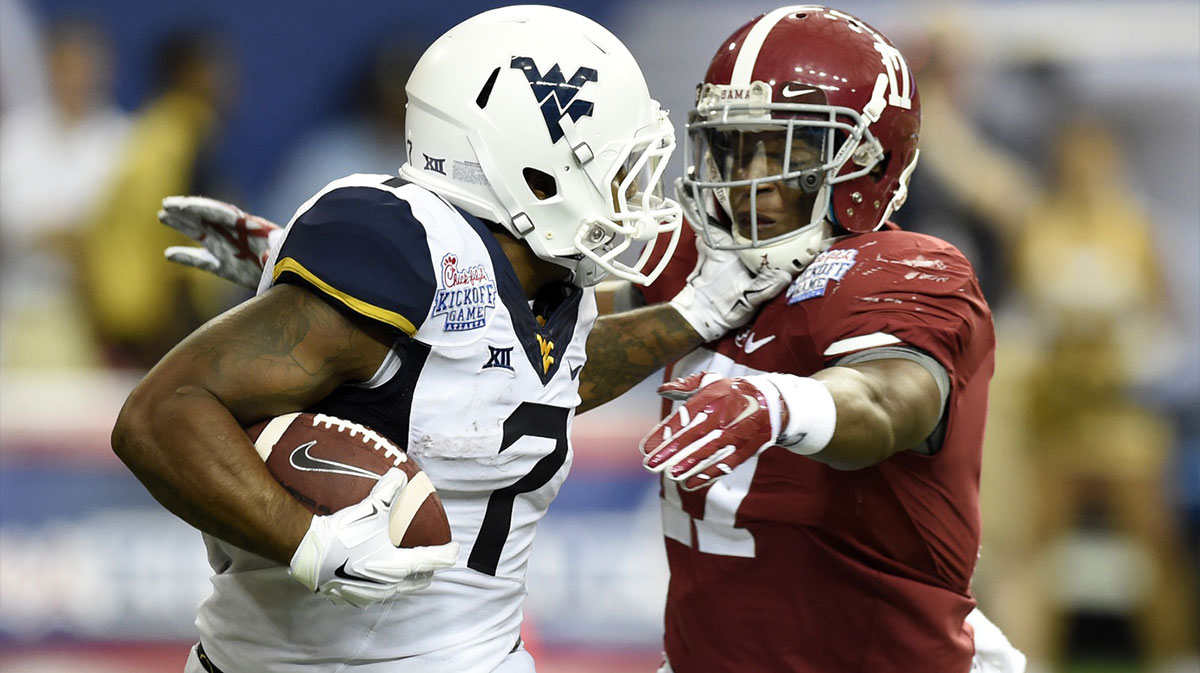 West Virginia Mountaineers running back Rushel Shell (7) stiff arms Alabama Crimson Tide running back Kenyan Drake (17) on a kick off during the third quarter of the 2014 Chick-fil-a kickoff game at Georgia Dome.