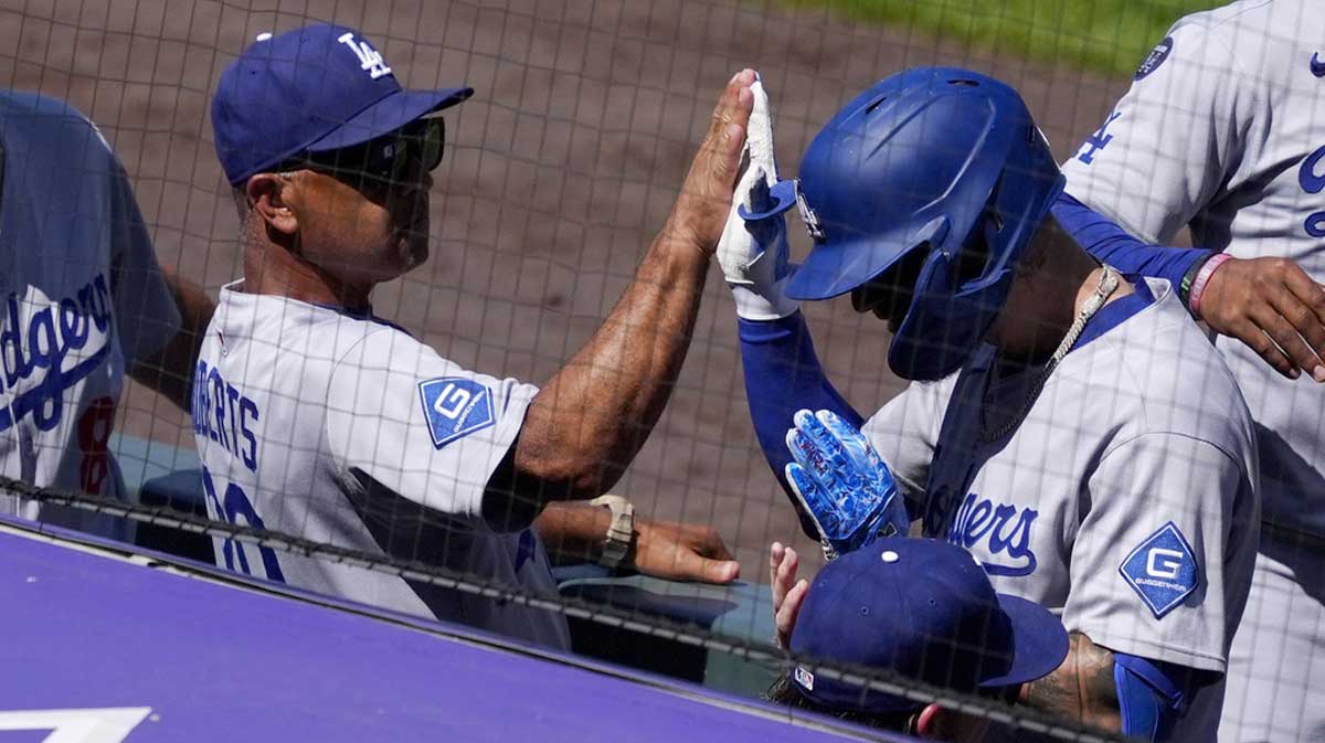 Los Angeles Dodgers manager Dave Roberts (30) high fives center fielder Andy Pages (44) following his solo home run in the inning at Coors Field.