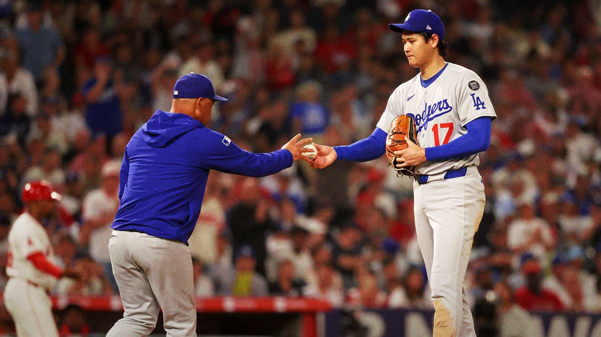 Los Angeles Dodgers two-way player Shohei Ohtani (17) hands the ball to manager Dave Roberts (30, left) during the fifth inning against the Los Angeles Angels at Angel Stadium.