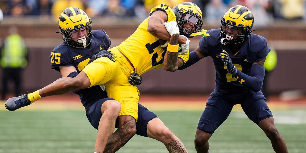 Team Maize wide receiver Donaven McCulley (13) makes a catch against Team Blue defensive back Mason Curtis (25), left, and defensive back Shamari Earls (2), right, during the first half of the spring game at Michigan Stadium