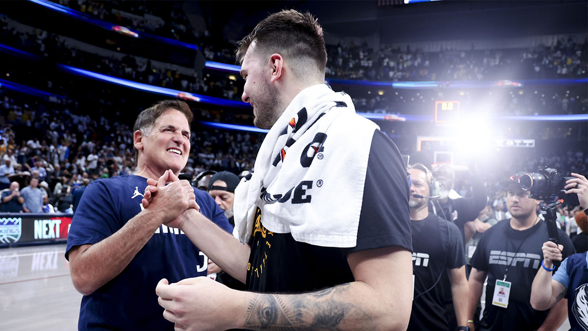 Lakers guard Luka Doncic (77) hugs Mark Cuban after the game against the Dallas Mavericks at American Airlines Center with Dirk Nowitzki in the background