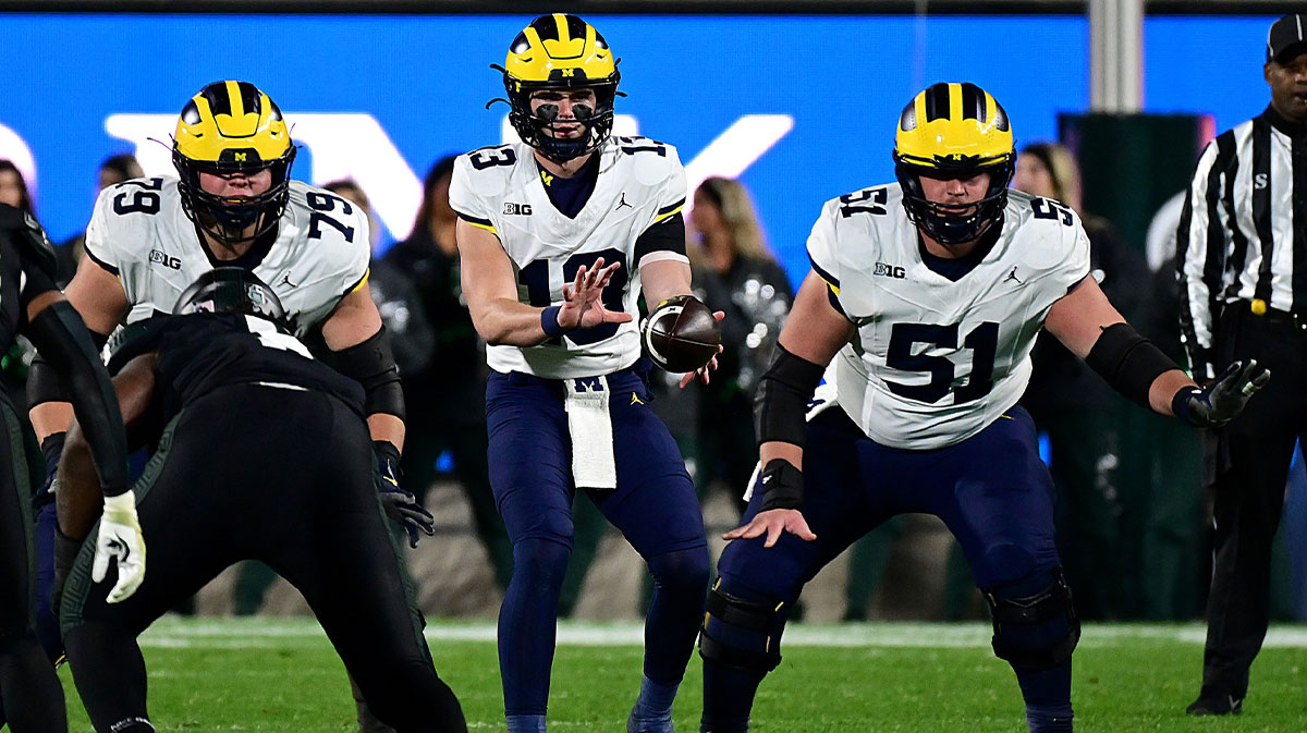 Michigan Wolverines quarterback Jack Tuttle (13) takes a snap from Michigan Wolverines Greg Crippen (51) in the fourth quarter against the Michigan State Spartans at Spartan Stadium.