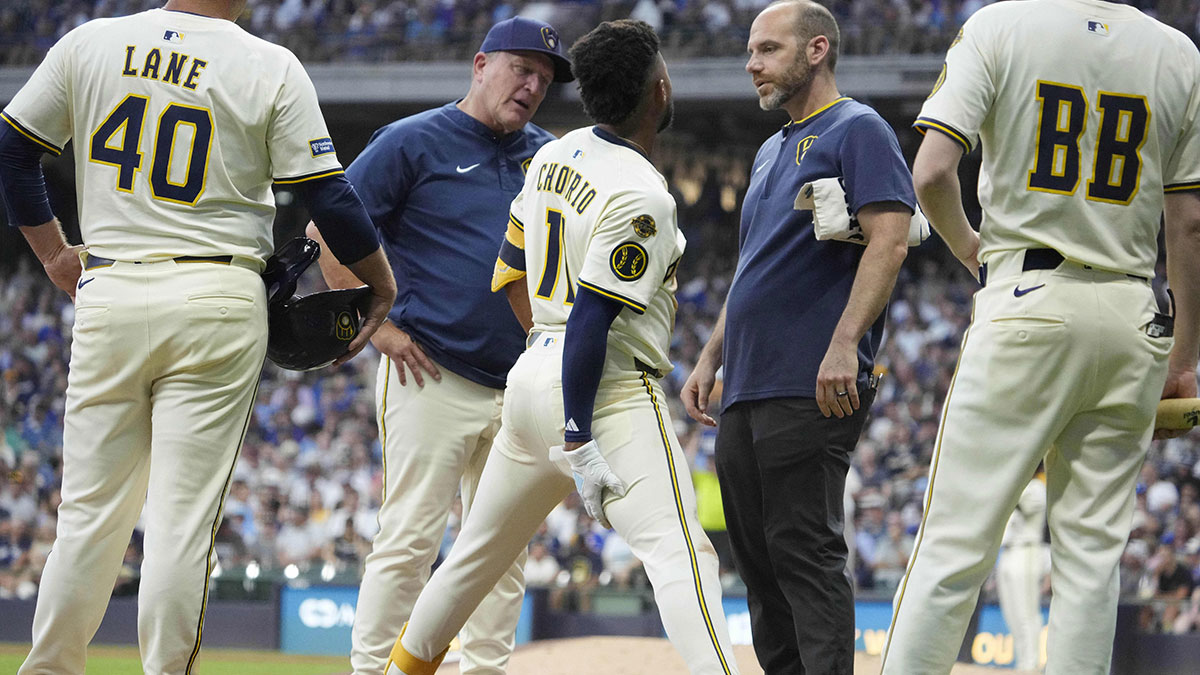 Milwaukee Brewers outfielder Jackson Chourio (11) grabs his hamstring after hitting a triple while manager Pat Murphy (49) and the trainer talk with him in the fifth inning against the Chicago Cubs at American Family Field. 