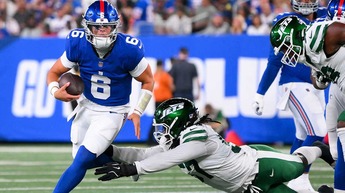 New York Giants quarterback Jaxson Dart (6) runs as New York Jets defensive end Kingsley Jonathan (57) defends during the first half at MetLife Stadium.
