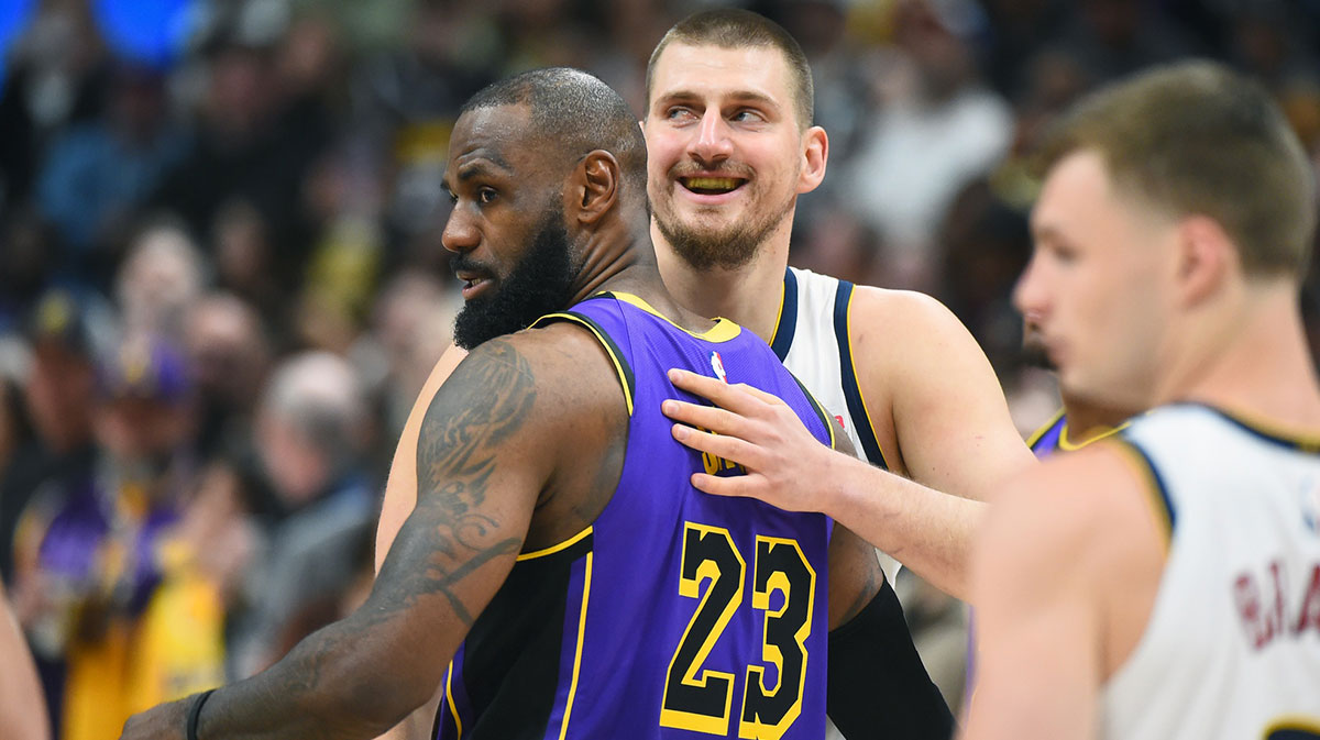 Denver Nuggets center Nikola Jokic (15) and Los Angeles Lakers forward LeBron James (23) hug before the game at Ball Arena.