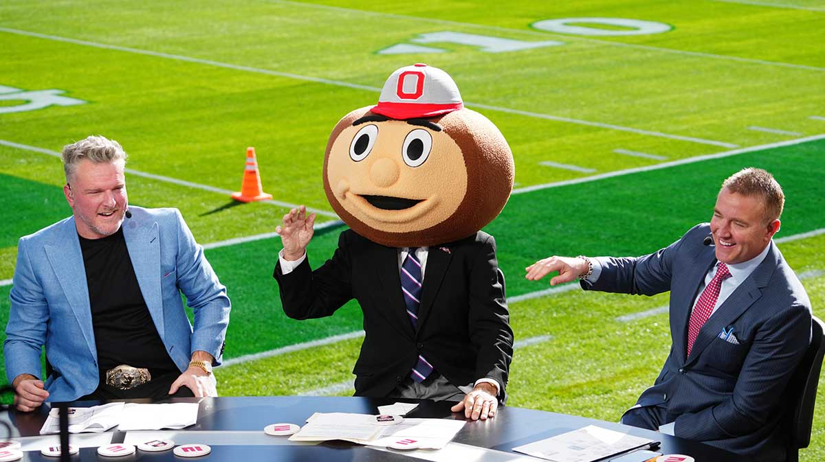 Lee Corso (center) wears a Buckeyes mascot head as Pat McAfee (left) and Kirk Herbstreit (right) watch at Rose Bowl Stadium.