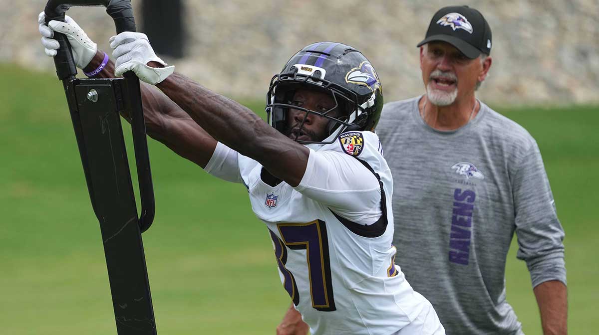Baltimore Ravens coach Chuck Pagano and cornerback Robert Longerbeam (37) work on drills during training camp at the Under Armour Performance Center.