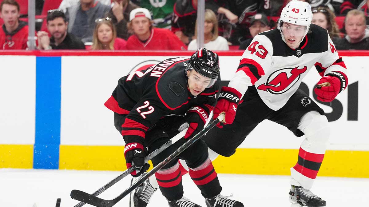 Carolina Hurricanes center Logan Stankoven (22) battles for the puck against New Jersey Devils defenseman Luke Hughes (43) during the third period of game one of the first round of the 2025 Stanley Cup Playoffs