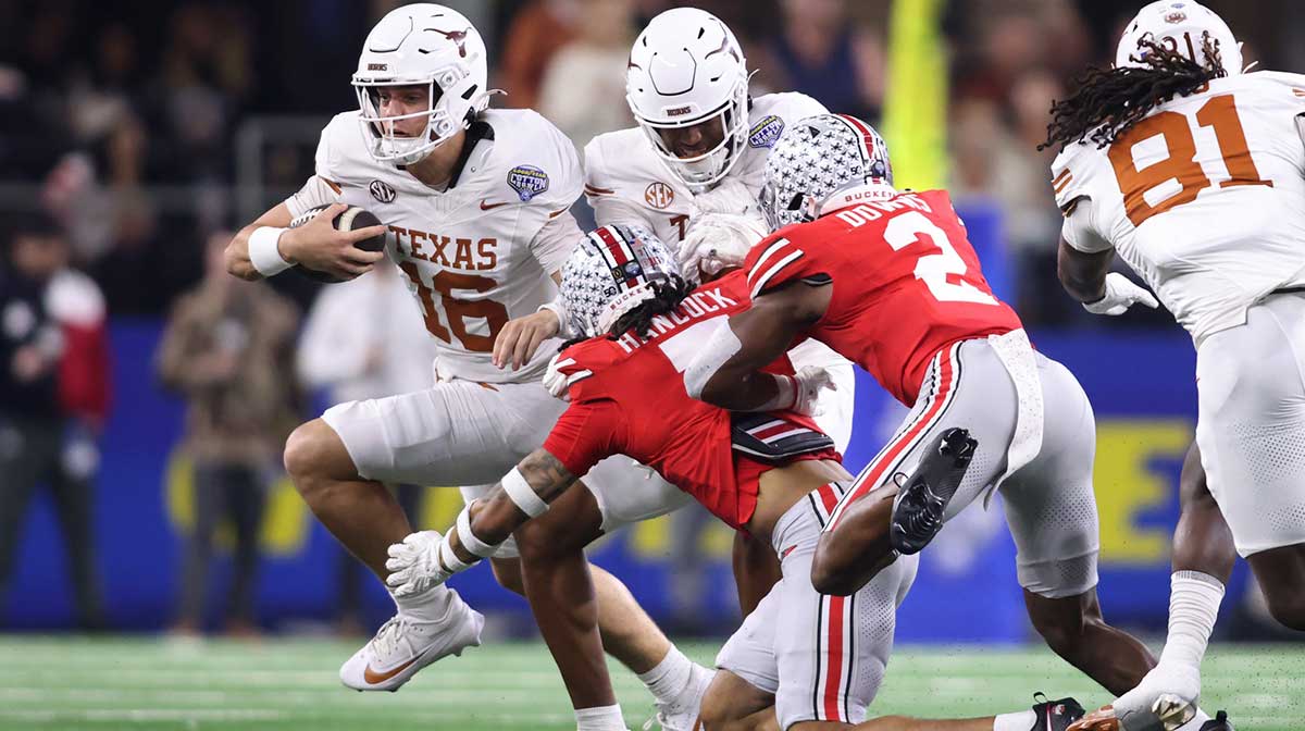 Texas Longhorns quarterback Arch Manning (16) runs against Ohio State Buckeyes cornerback Jordan Hancock (7) and safety Caleb Downs (2) during the second quarter of the College Football Playoff semifinal in the Cotton Bowl at AT&T Stadium.