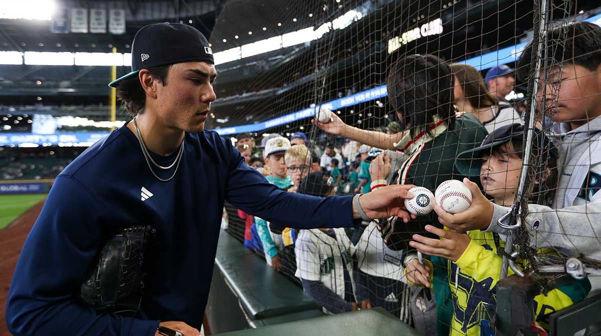 Seattle Mariners starting pitcher Bryan Woo (22) signs a fans ball before the game against the Chicago White Sox at T-Mobile Park.