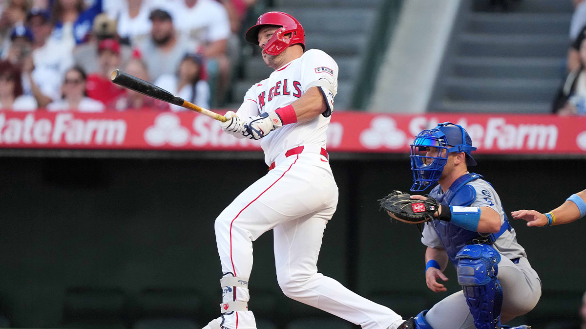 Los Angeles Angels designated hitter Mike Trout (27) hits a single in the first inning as Los Angeles Dodgers catcher Dalton Rushing (68) watches at Angel Stadium.