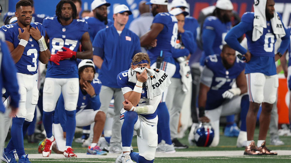 New York Giants quarterback Jaxson Dart (6), center, looks on with teammates are medical staff tend to cornerback TJ Moore (30) after an injury during the second half against the New England Patriots at MetLife Stadium.
