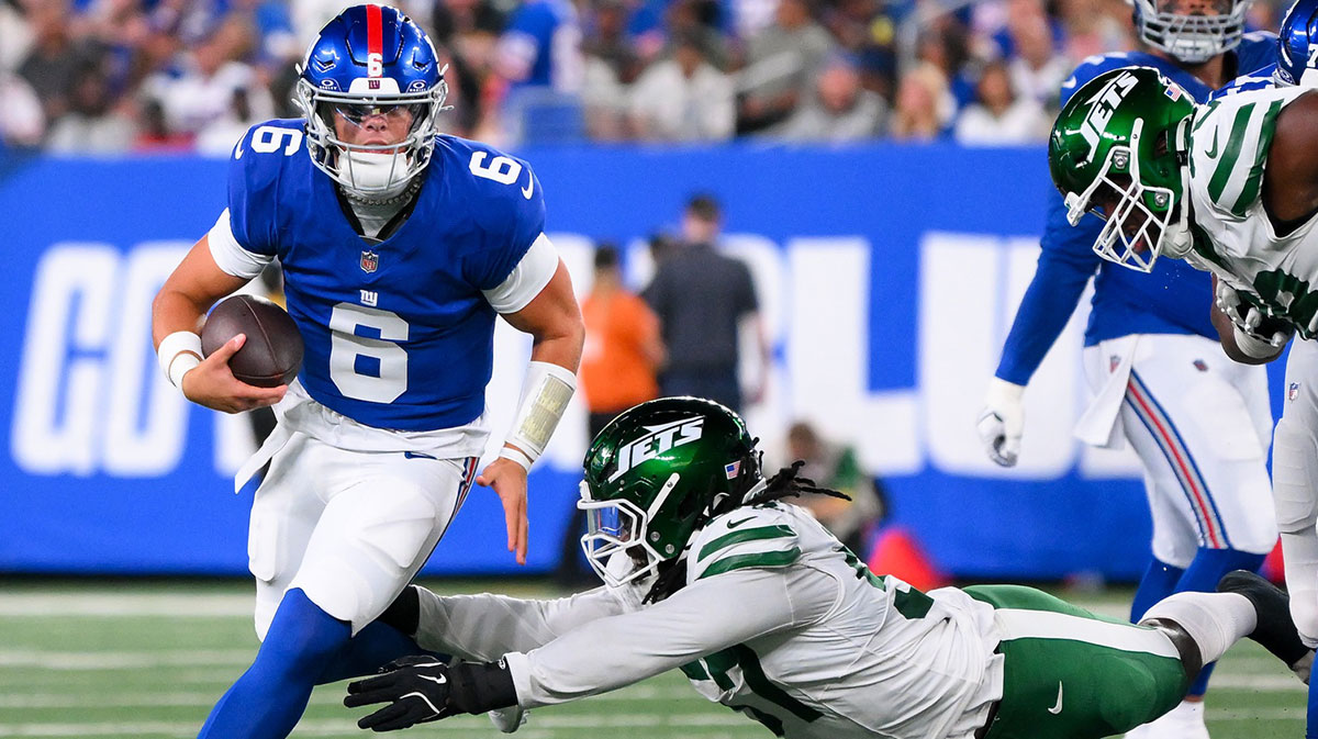 New York Giants quarterback Jaxson Dart (6) runs as New York Jets defensive end Kingsley Jonathan (57) defends during the first half at MetLife Stadium.