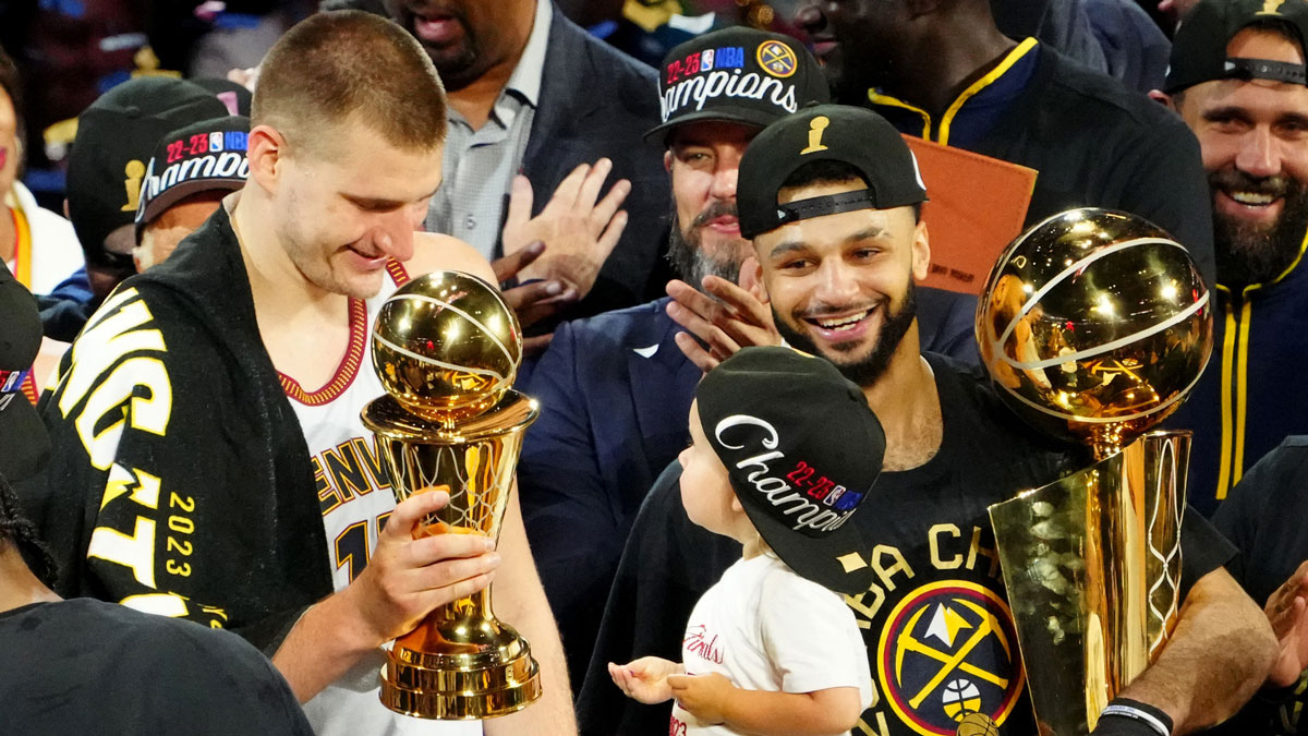 Denver Nuggets center Nikola Jokic (15) celebrates with the Bill Russell NBA Finals MVP Award as guard Jamal Murray (27) holds the Larry O'Brien Trophy after the Nuggets won the 2023 NBA Championship against the Miami Heat at Ball Arena.