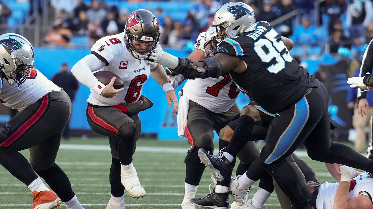 Tampa Bay Buccaneers quarterback Baker Mayfield (6) keeps the ball and runs with Carolina Panthers defensive tackle Derrick Brown (95) reaching out for the attempted stop during the second half at Bank of America Stadium.