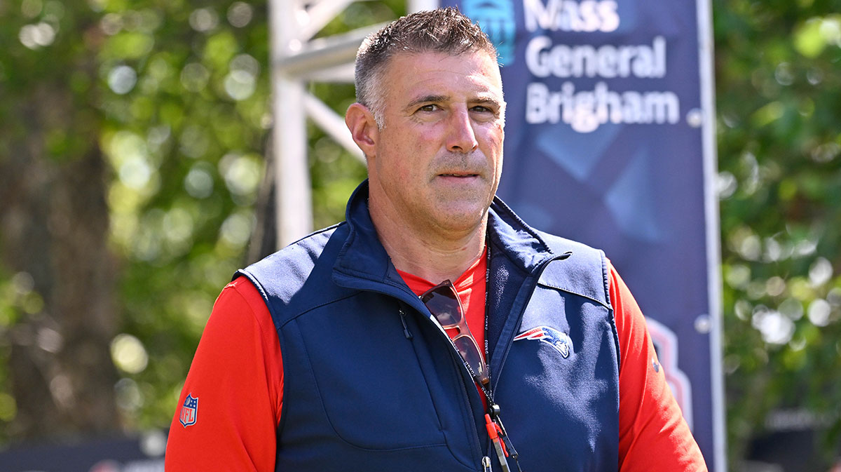 Patriots head coach Mike Vrabel heads to the practice fields for training camp at Gillette Stadium with the Commanders logo in the background