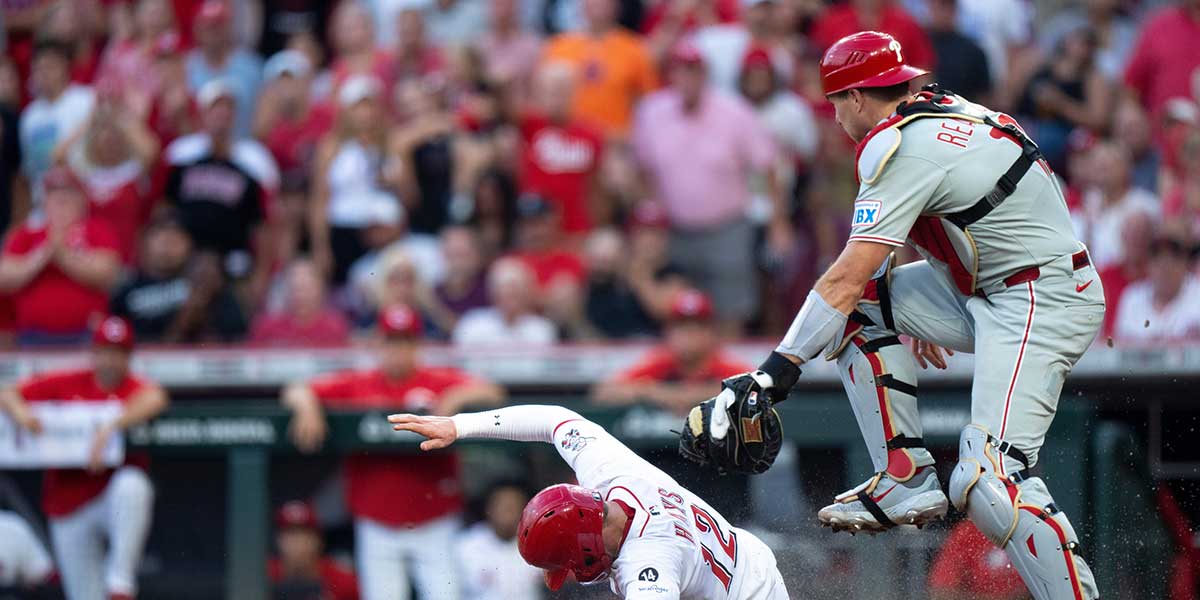 Cincinnati Reds left fielder Austin Hays (12) slides into home to score off of Cincinnati Reds third baseman Noelvi Marte (16) as Philadelphia Phillies catcher J.T. Realmuto (10) drops the throw in the sixth inning between Cincinnati Reds and Philadelphia Phillies at Great American Ball Park in Cincinnati on Aug. 13, 2025.