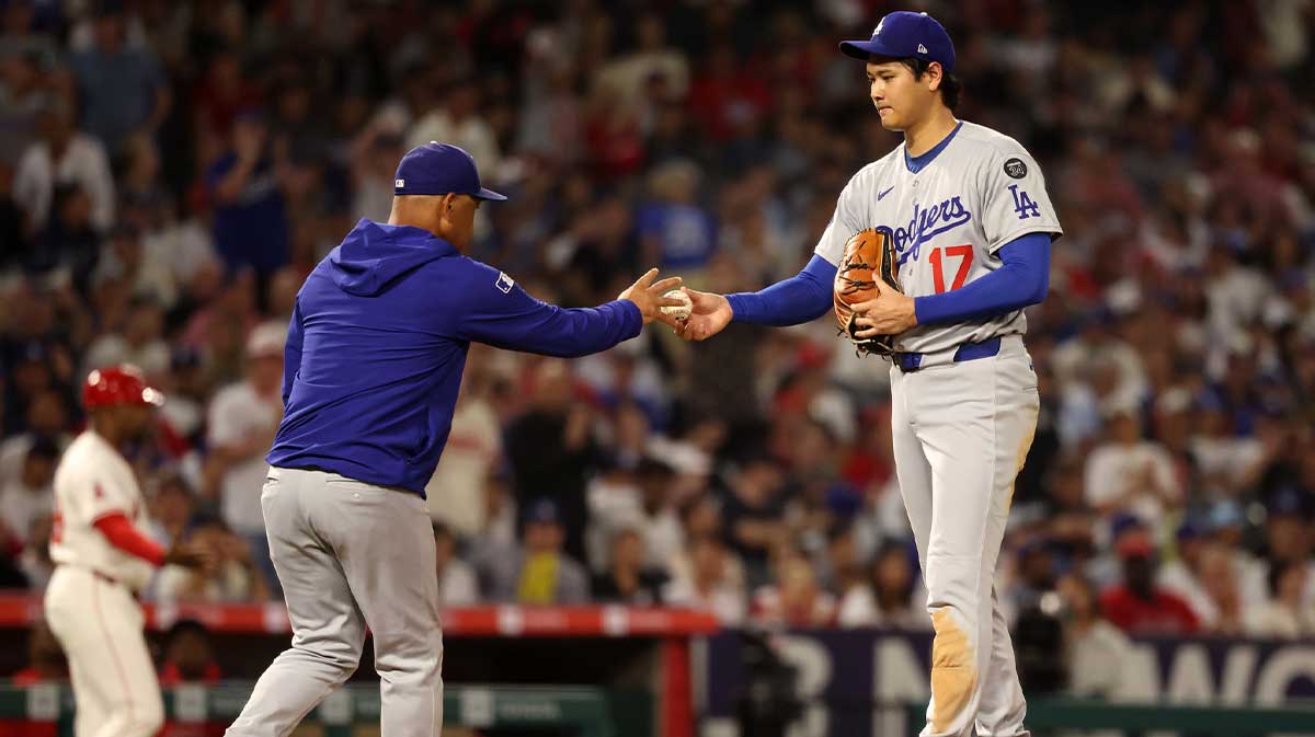 Los Angeles Dodgers two-way player Shohei Ohtani (17) hands the ball to manager Dave Roberts (30, left) during the fifth inning against the Los Angeles Angels at Angel Stadium.
