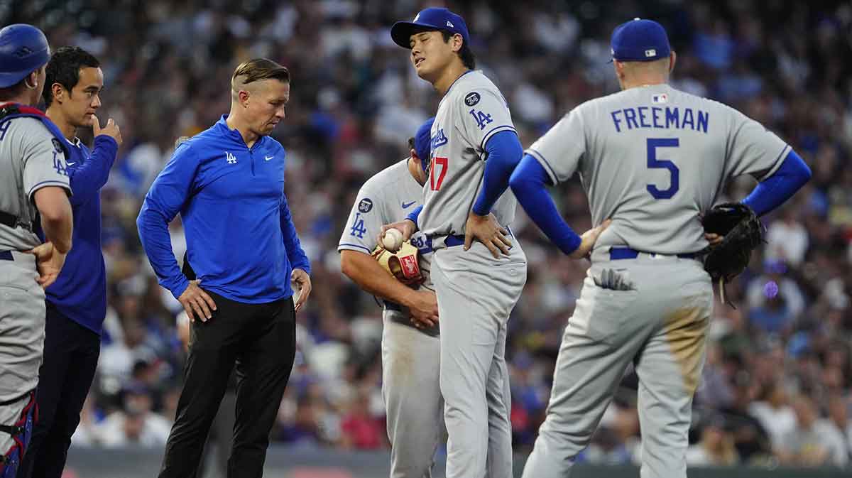 Los Angeles Dodgers starting pitcher Shohei Ohtani (17) is looked at by trainers in the fourth inning against the Colorado Rockies at Coors Field.