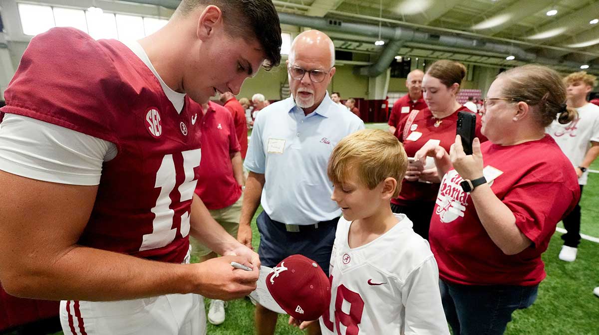 Alabama Crimson Tide players and coaches participate in a media day with reporters and fans at the Hank Crisp Indoor Practice Facility. Quarterback Ty Simpson signs an autograph for fan Bennett Martina.
