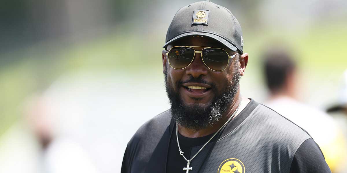 Steelers head coach Mike Tomlin speaks to the media during training camp at Saint Vincent College with the Buccaneers logo in the background